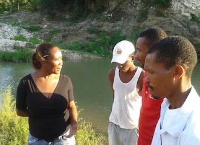 Dr. Miliane Clermont talking with 3 men in front of a stream.