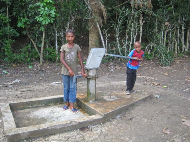 Two young children pumping water